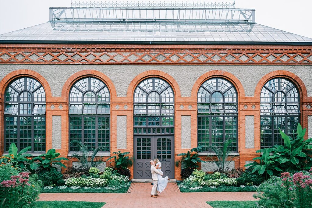 Couple doing a lift in front of greenhouse at Biltmore Estate Engagement Session