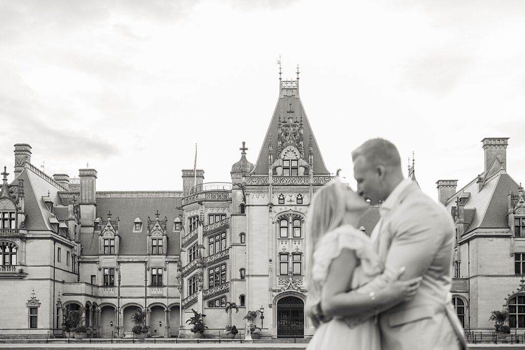 couple kissing in front of the biltmore estate at engagement session