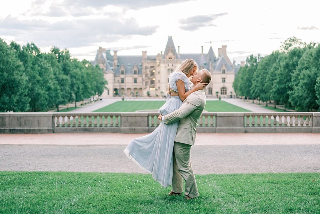 Couple lift kiss at Biltmore's Esplanade during their Biltmore Estate Engagement Session