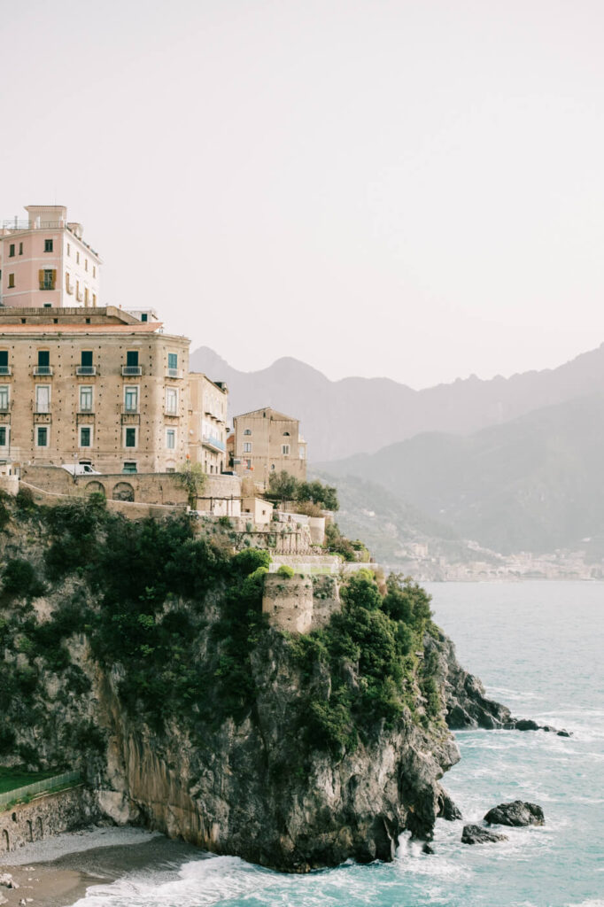 Historic Italian villa perched atop a towering cliff, overlooking the turquoise waters of the Amalfi Coast.