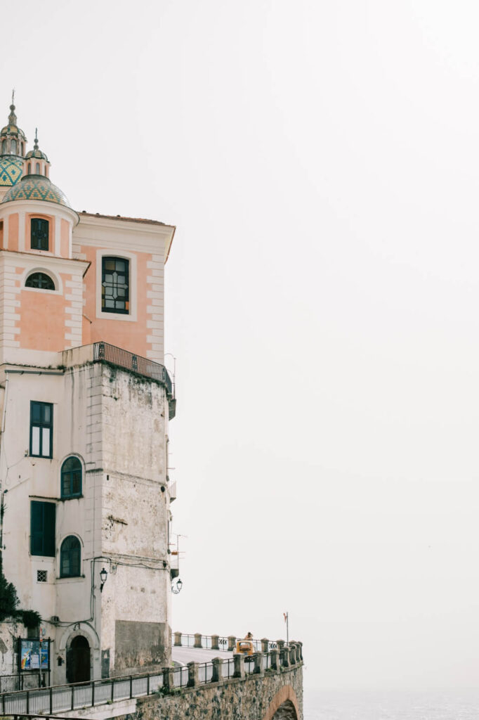 Pastel pink church tower perched along the Amalfi cliffside, showcasing classic Italian coastal architecture.