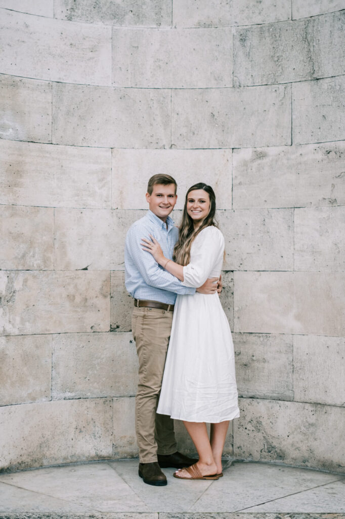 Romantic couple portrait in Florence, Italy – A couple embraces in front of a grand stone wall, dressed elegantly for their destination session in Florence.