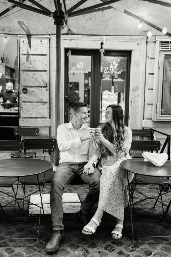 Café date in Rome – A black and white image of the couple toasting with small espresso cups at an outdoor café, sharing a quiet, romantic moment in the heart of Rome.