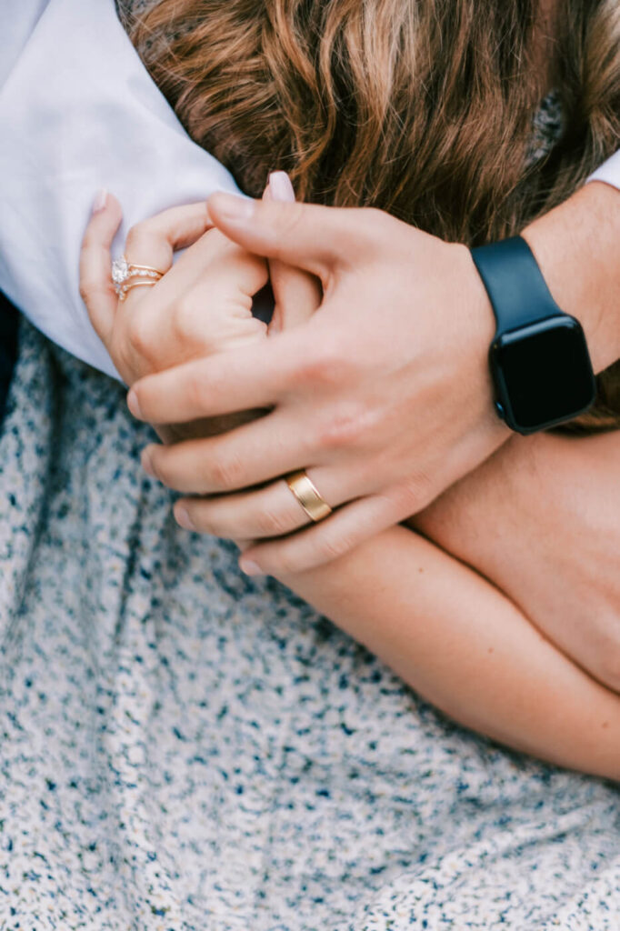 Close-up of hands with wedding rings – A detailed shot of the couple’s intertwined hands, highlighting their wedding rings and a delicate engagement ring, symbolizing their love and commitment.