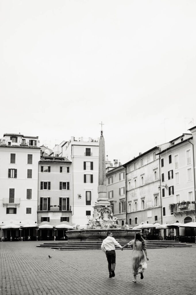 Black and white moment at Piazza della Rotonda – A black and white capture of the couple walking hand in hand through Piazza della Rotonda, with the towering obelisk and historic architecture behind them.