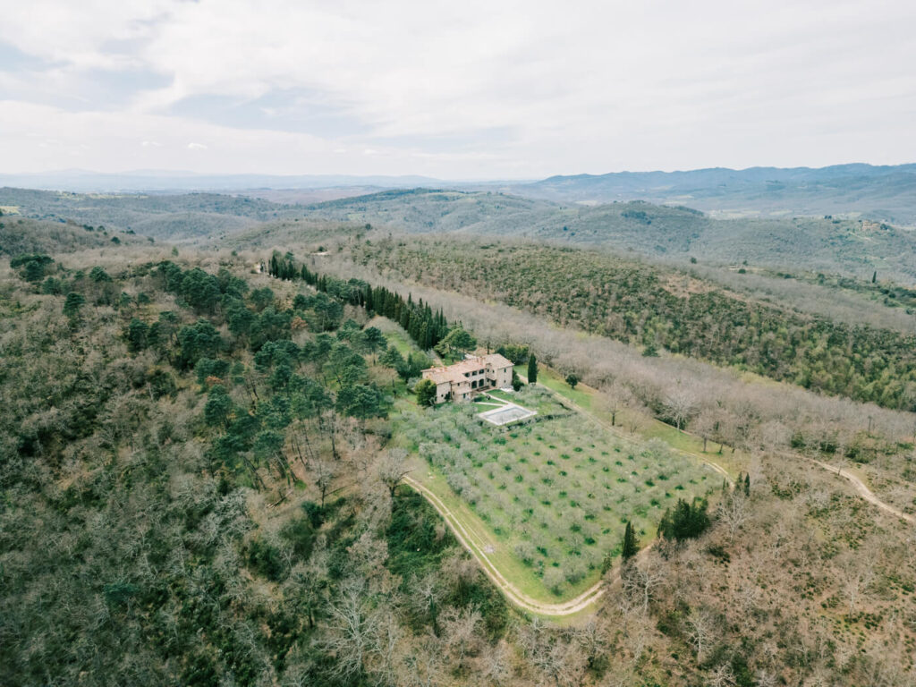 Stunning aerial view of Villa Olimpia, a Tuscany wedding venue, surrounded by rolling hills, olive trees, and breathtaking Italian countryside.