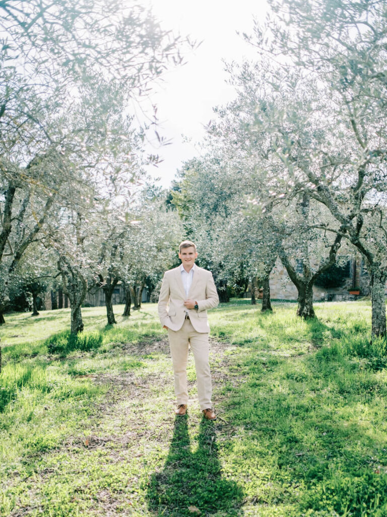 Groom standing in an olive grove, bathed in golden sunlight, ready for his romantic Tuscany wedding.