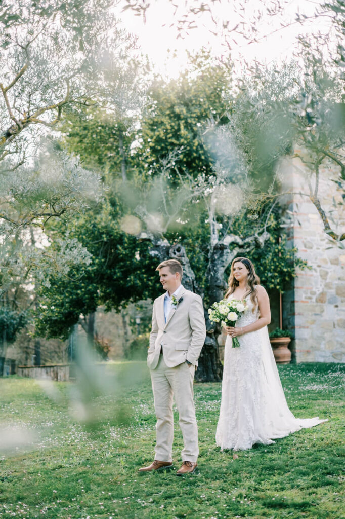 Bride approaching the groom for an emotional first look, framed by Tuscany villa stone walls and olive trees.