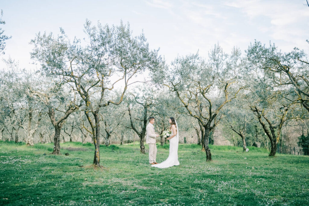 Bride and groom sharing heartfelt private vows, surrounded by olive trees.