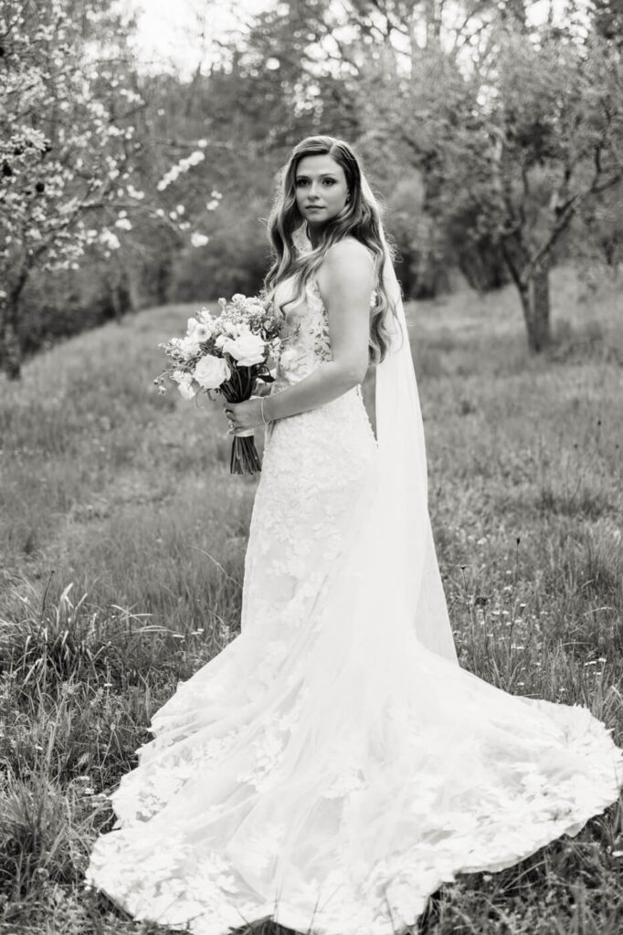 Bride holding a lush bouquet, surrounded by the serene beauty of Tuscany.