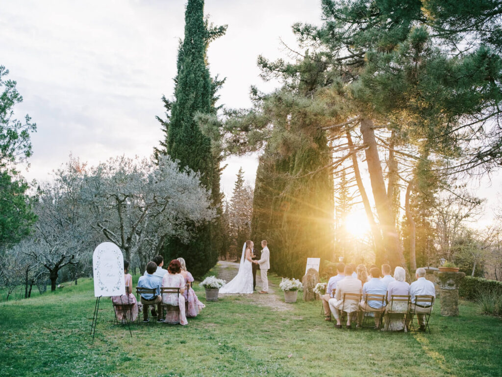 A sun-drenched ceremony in the Tuscan countryside, with golden light filtering through the cypress trees.