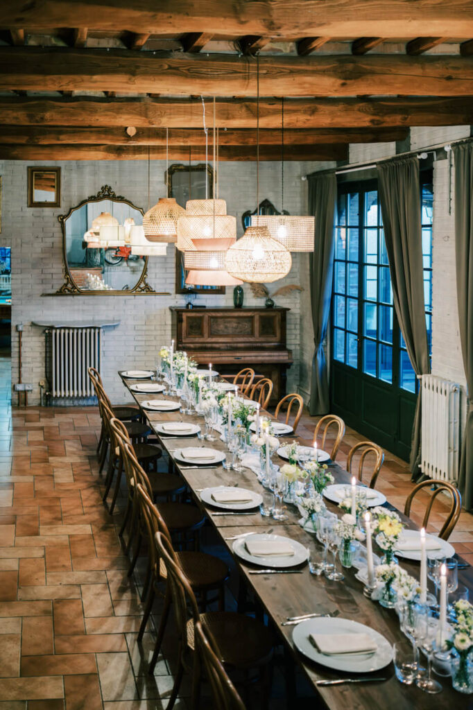 A warm and inviting reception – A long, rustic table adorned with flickering candles and fresh florals awaits guests in the villa’s cozy dining hall.