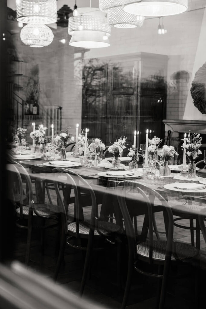 An intimate dinner reflection – A black-and-white view through the villa’s windows captures the soft glow of candlelight and a table filled with loved ones.