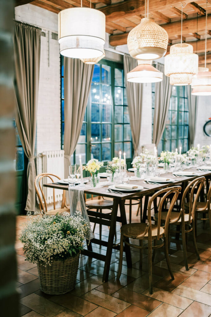 A dreamlike Italian ambiance – Soft woven light fixtures cast a warm glow over the candlelit reception space, where laughter and conversation fill the air.