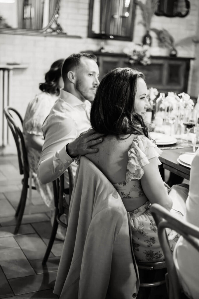 A guest lovingly places his hand on his partner’s back as they share a quiet moment at the reception table.