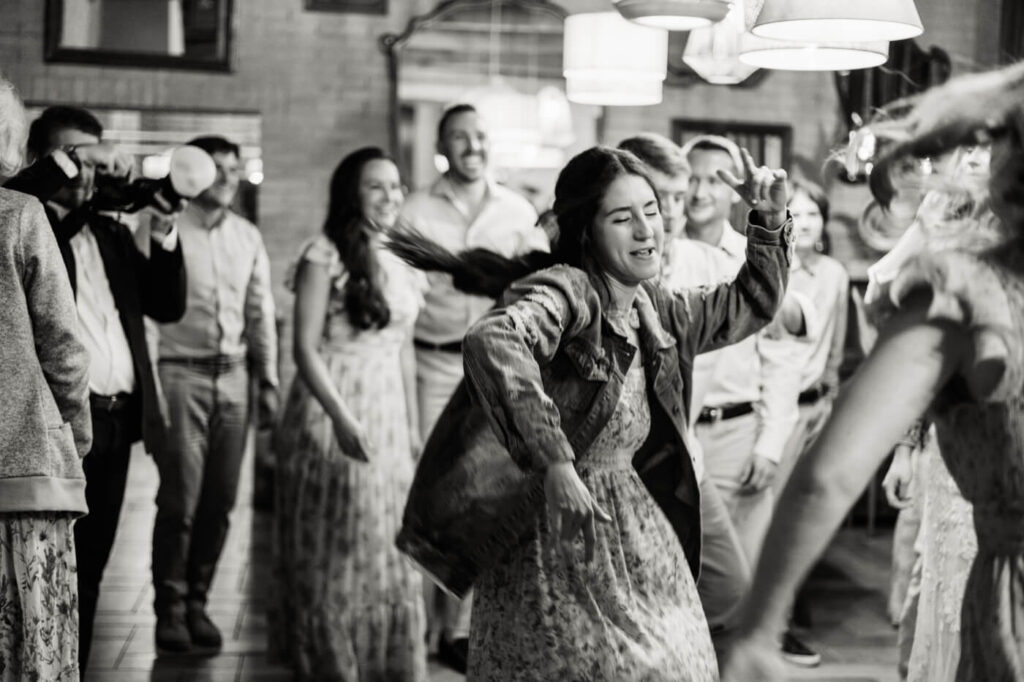 A guest twirls on the dance floor, her joyful energy captured in motion as others smile and watch.