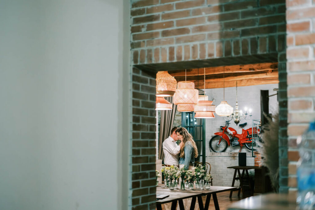 A framed view of the bride and groom sharing a quiet embrace under warm, romantic lights in the reception space.