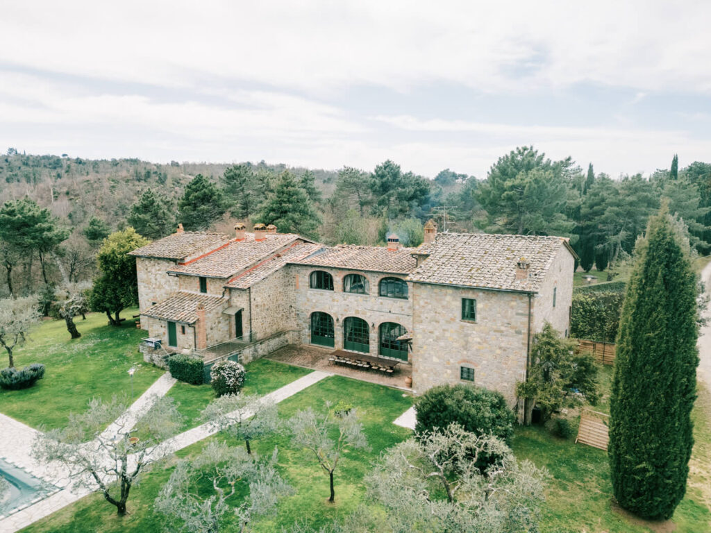 Villa Olimpia in the Tuscan countryside – A stunning aerial view of the historic villa surrounded by lush greenery, olive groves, and winding stone paths.