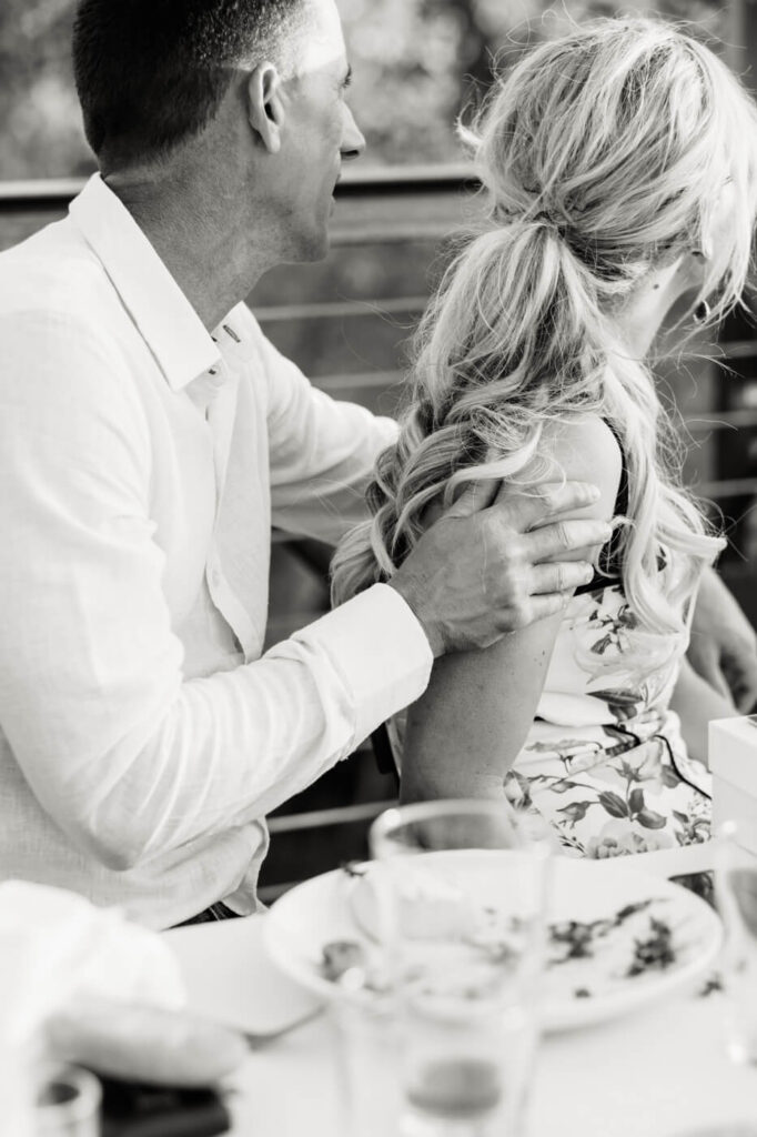 Groom Holding Bride’s Shoulder During Finley Farm Bridge Rehearsal Dinner – An intimate gesture as the groom places a comforting hand on his bride-to-be’s shoulder while they soak in the moment.