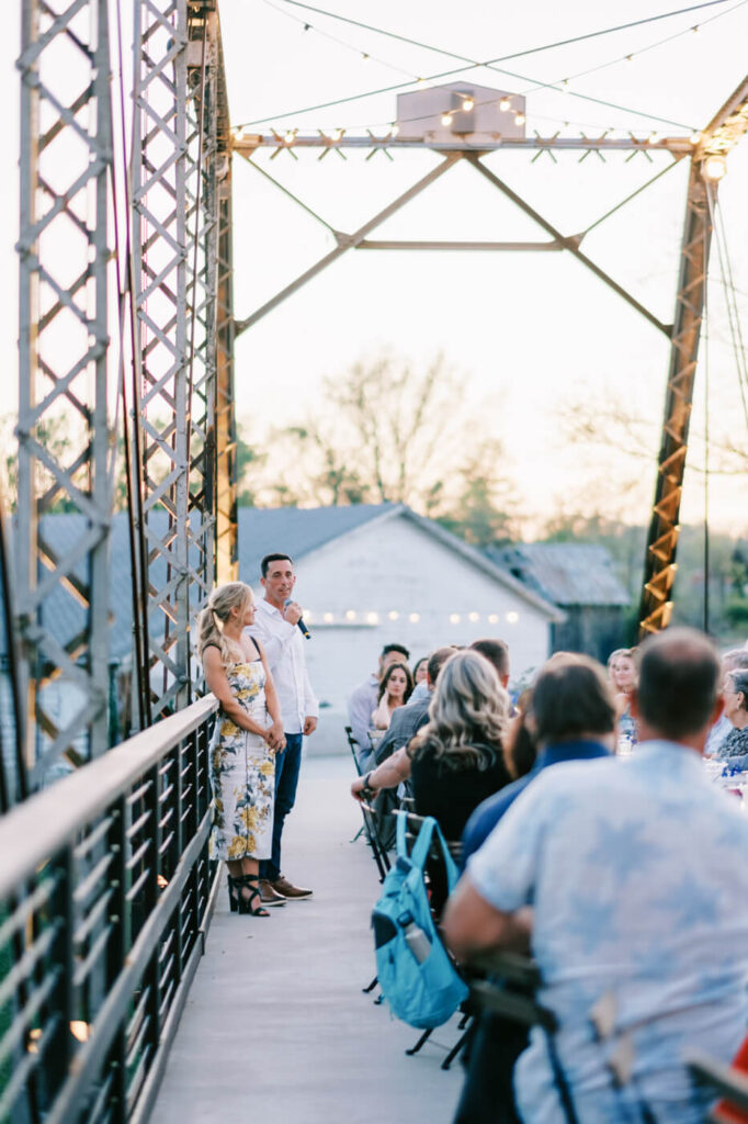 Bride and Groom Giving Speech on Finley Farm Bridge at Rehearsal Dinner – The couple stands before their guests, sharing words of gratitude and excitement for their wedding day at Finley Farm Bridge.