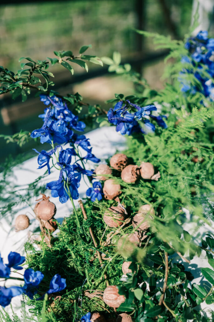 Close-up of floral centerpiece at Finley Farms Bridge – Lush greenery, deep blue blooms, and dried accents create a natural and elegant table arrangement at the rehearsal dinner.