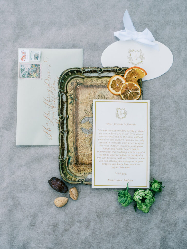 Elegant Wedding Invitation Suite – A wedding invitation suite displayed on a vintage gold tray, adorned with dried citrus slices, delicate calligraphy, and a soft ivory ribbon.