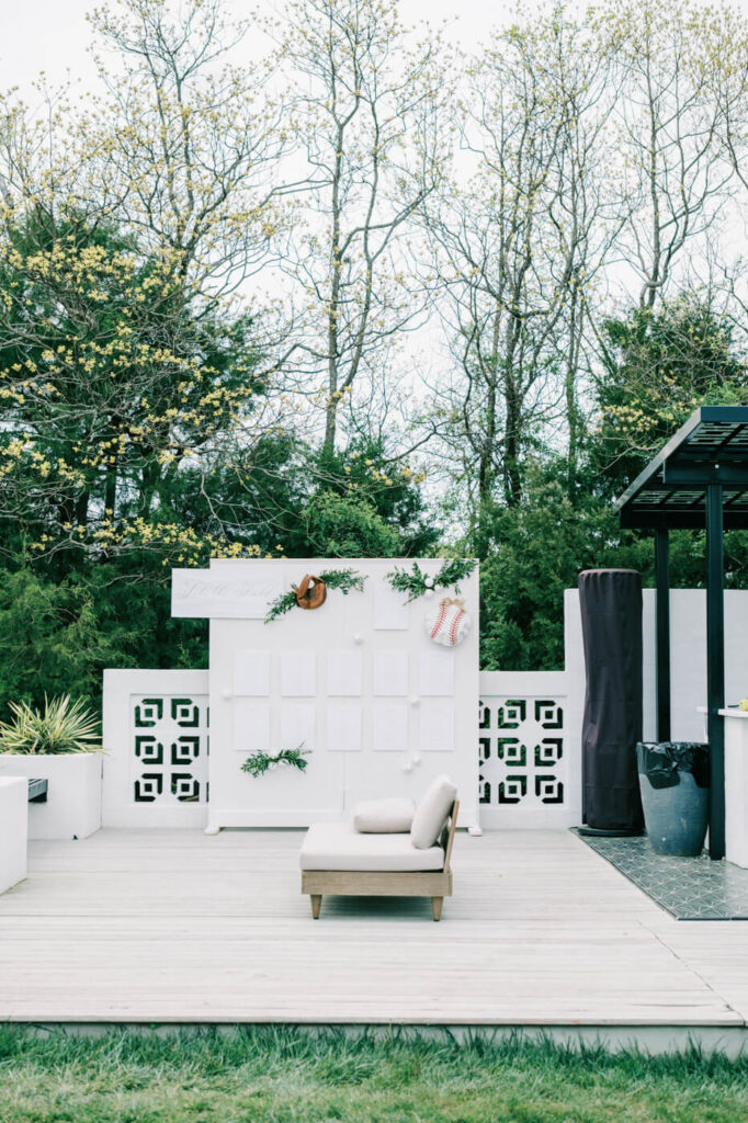 Wedding seating chart at The Greenhouse Two Rivers with baseball glove decor – A modern white seating chart display at The Greenhouse Two Rivers, featuring a mounted vintage baseball glove holding a ball, with name cards and fresh greenery accents.