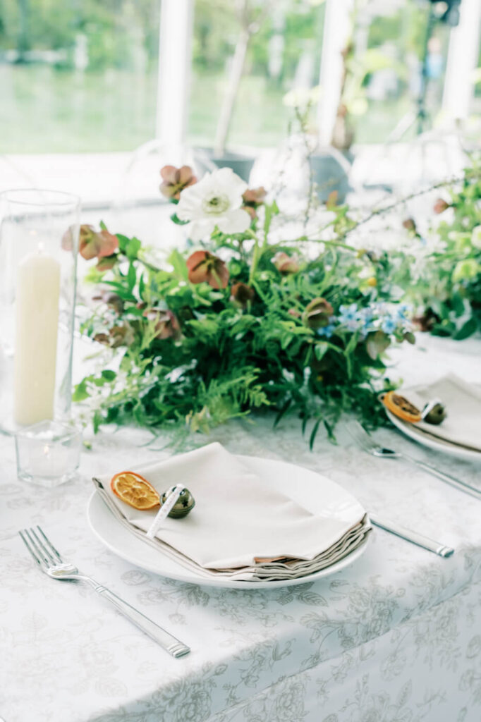 Fine art wedding table setting at Two Rivers Greenhouse – A meticulously styled tablescape with white floral linens, soft candlelight, and nature-inspired floral centerpieces, reflecting a refined wedding design at Two Rivers Greenhouse.