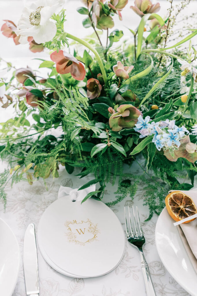 Elegant reception table styling at Two Rivers Greenhouse wedding – A refined wedding tablescape featuring a monogrammed menu card, fresh floral centerpiece, and natural elements, enhancing the sophisticated setting of Two Rivers Greenhouse.