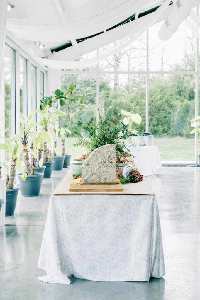 Elegant reception table at Greenhouse Two Rivers wedding – A stylishly set reception table with greenery-filled centerpieces and a natural stone table number at Greenhouse Two Rivers.