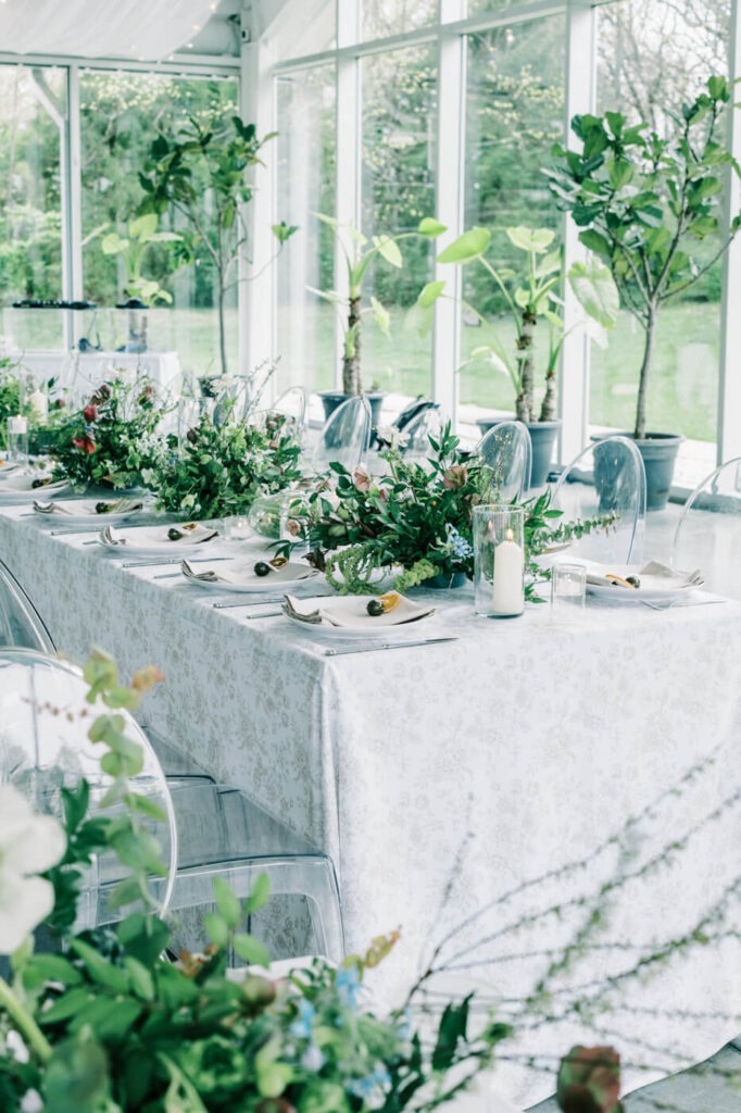 Luxury wedding tablescape at Greenhouse Two Rivers – A long wedding table adorned with greenery, candlelit accents, and elegant place settings inside the light-filled greenhouse venue.