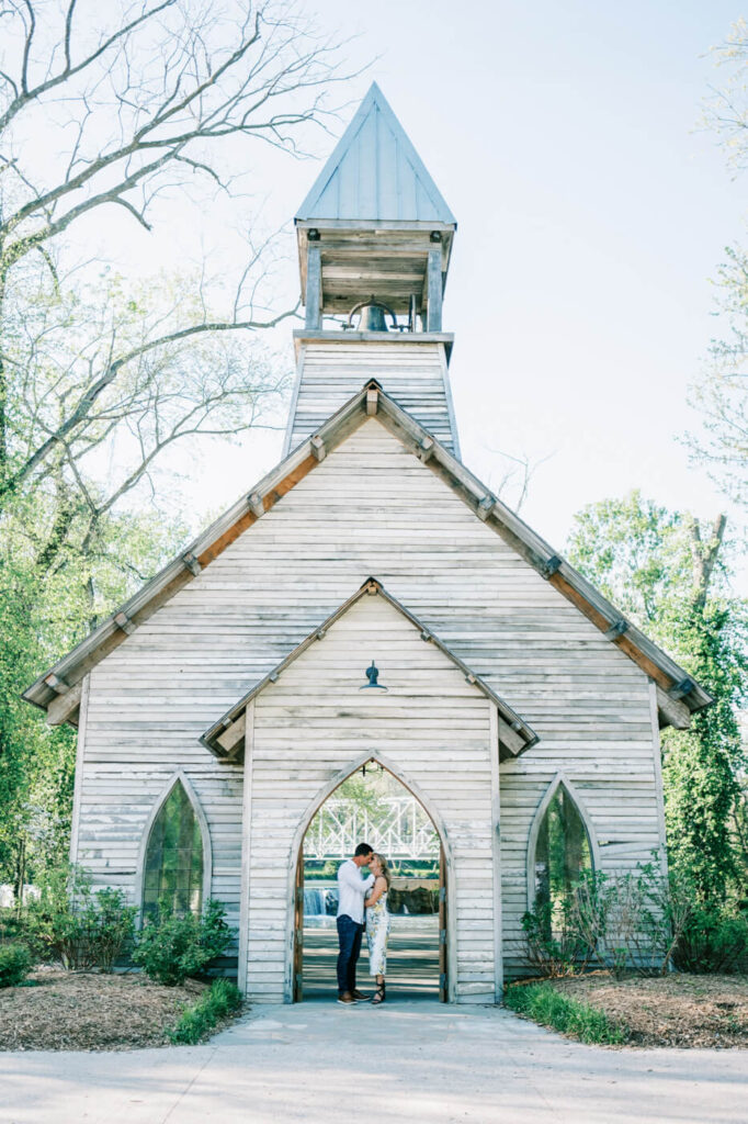 Couple sharing a moment outside the chapel at Finley Farms – Kandis and Andrew embrace in front of the wooden chapel with the scenic bridge visible in the background.