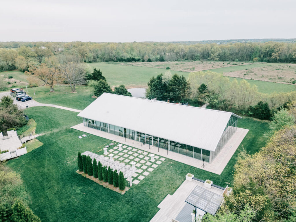 Aerial view of the Greenhouse Two Rivers ceremony courtyard – A breathtaking drone shot capturing the open-air ceremony courtyard with a modern greenhouse structure in Missouri.