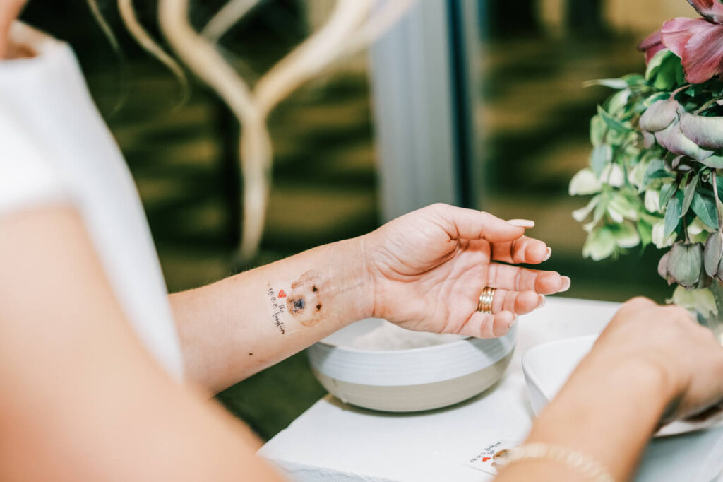 Bride’s Custom Dog Tattoo - A close-up of the bride’s wrist showcasing a temporary tattoo of a dog’s face with a red heart, a sweet tribute to a beloved pet.