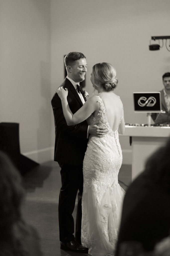 Bride and groom enjoying their first dance on the carriage house floor at Merrimon-Wynne House as guests watch from nearby tables.