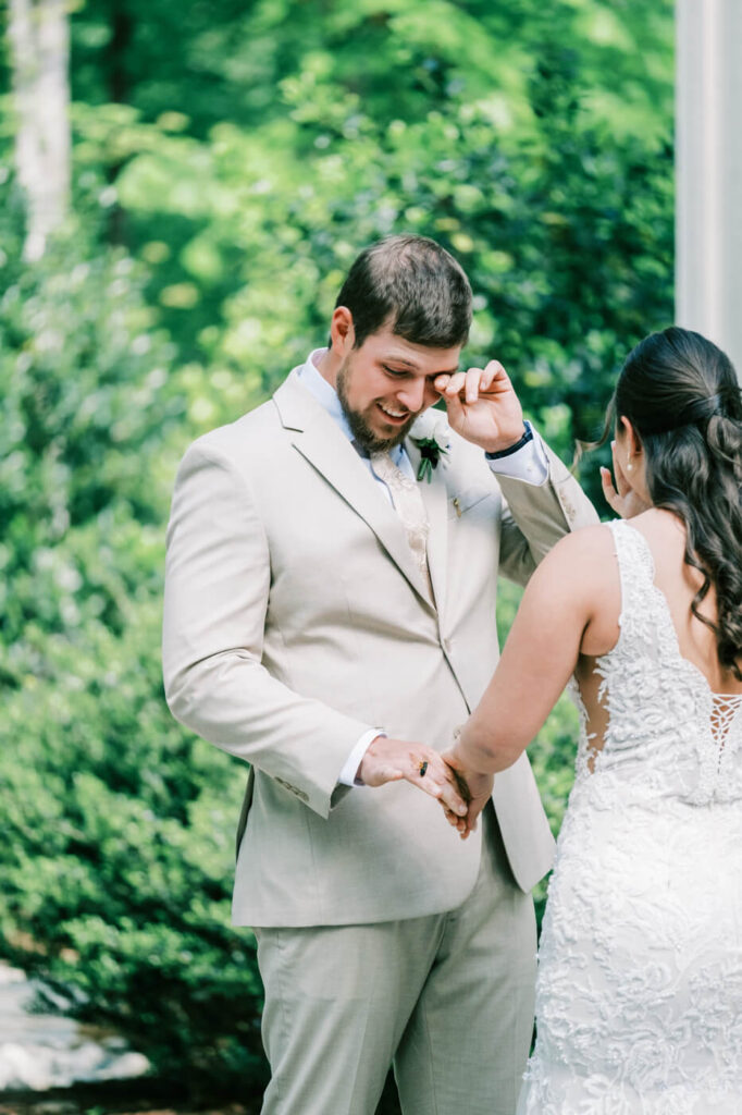 Groom wipes away a tear during an emotional first look with the bride at their romantic Carolina Grove wedding.