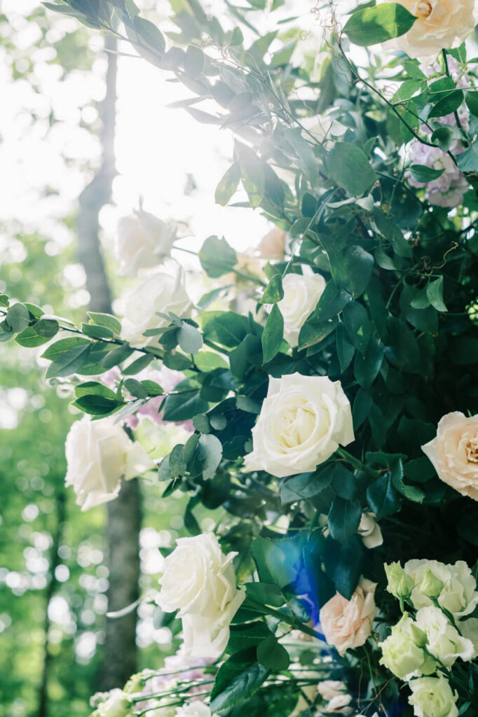 Close-up of wedding floral arrangements with soft white and blush roses, bathed in golden sunlight at Carolina Grove.