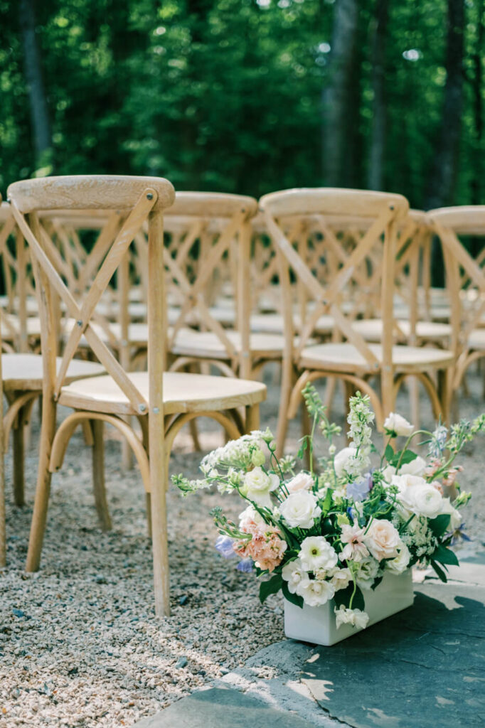 Rows of wooden chairs line the outdoor ceremony space at Carolina Grove, with floral arrangements adding a soft and romantic ambiance.