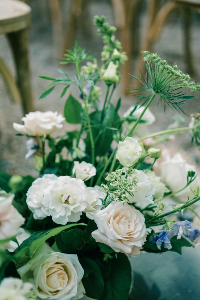 A close-up of the wedding ceremony aisle floral arrangement, soft pastels and greenery.