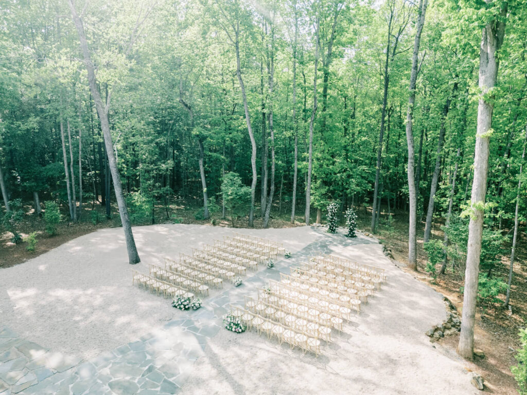 A serene aerial view of the outdoor wedding ceremony setup at Carolina Grove, surrounded by towering trees with chairs neatly arranged in rows.