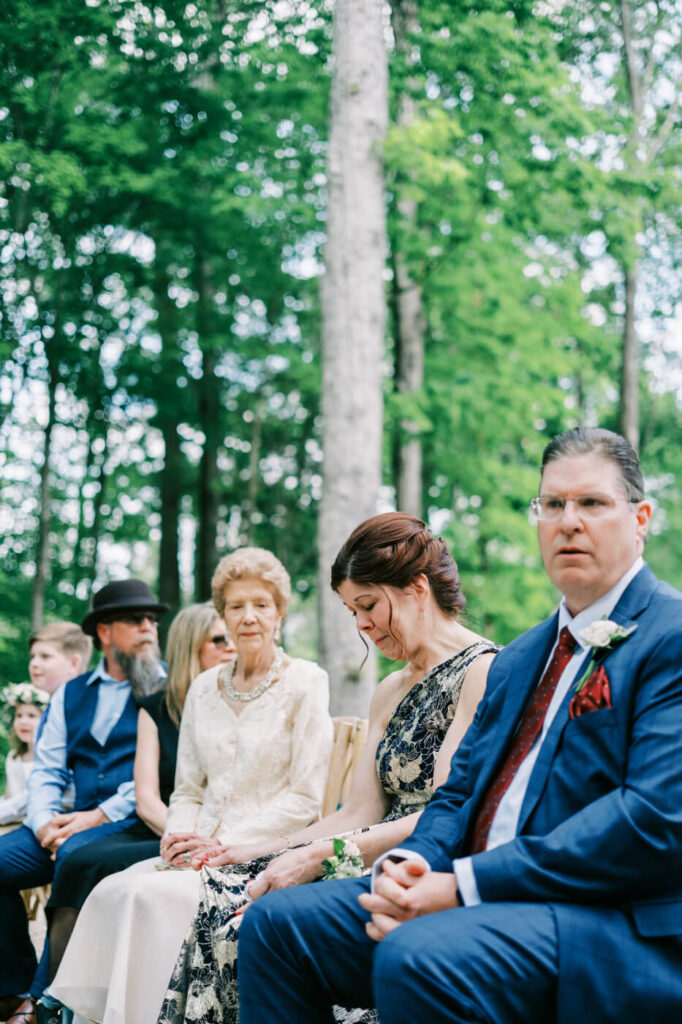 Emotional moment captured of family members seated at the ceremony, with a teary-eyed mother clasping her hands in reflection.