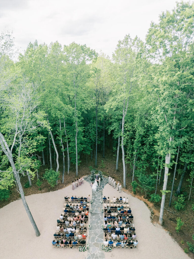 Aerial Ceremony View – A stunning bird’s-eye view of the couple’s ceremony in a forest clearing, surrounded by guests and tall trees.