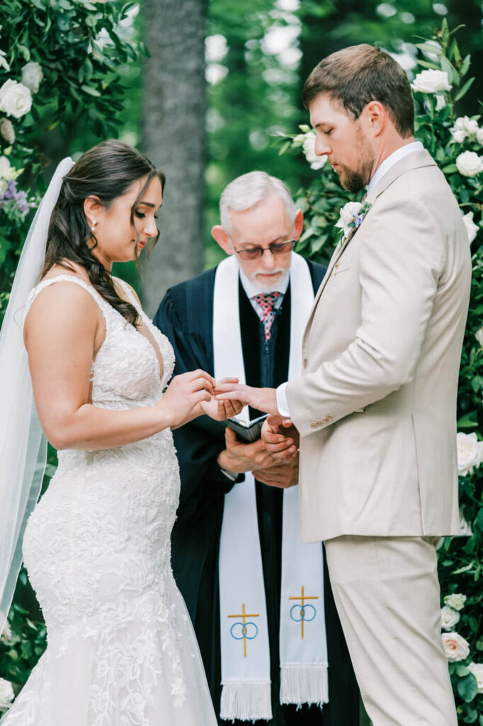 Exchanging Rings – The bride delicately places the wedding band on her groom’s finger as the officiant reads the vows.