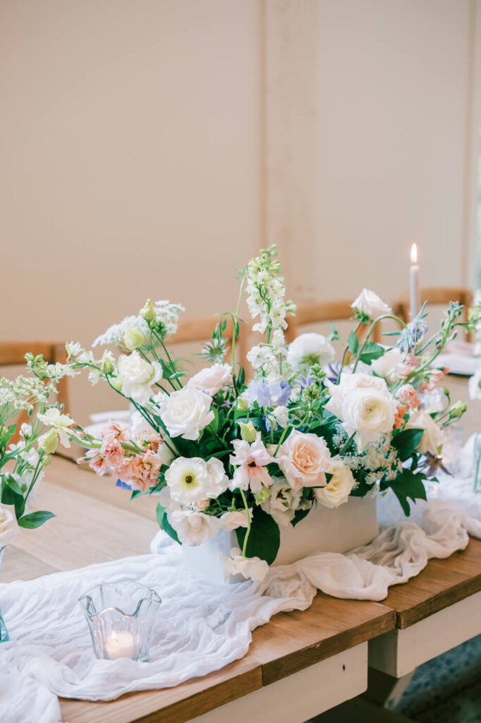 Lush floral centerpiece with pastel blooms and candlelight on a wedding reception table