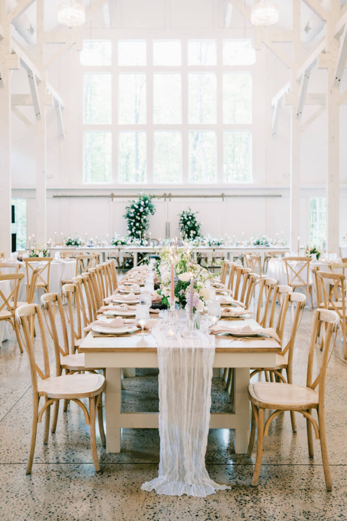 Long, elegant reception table with a flowing white runner and delicate floral arrangements