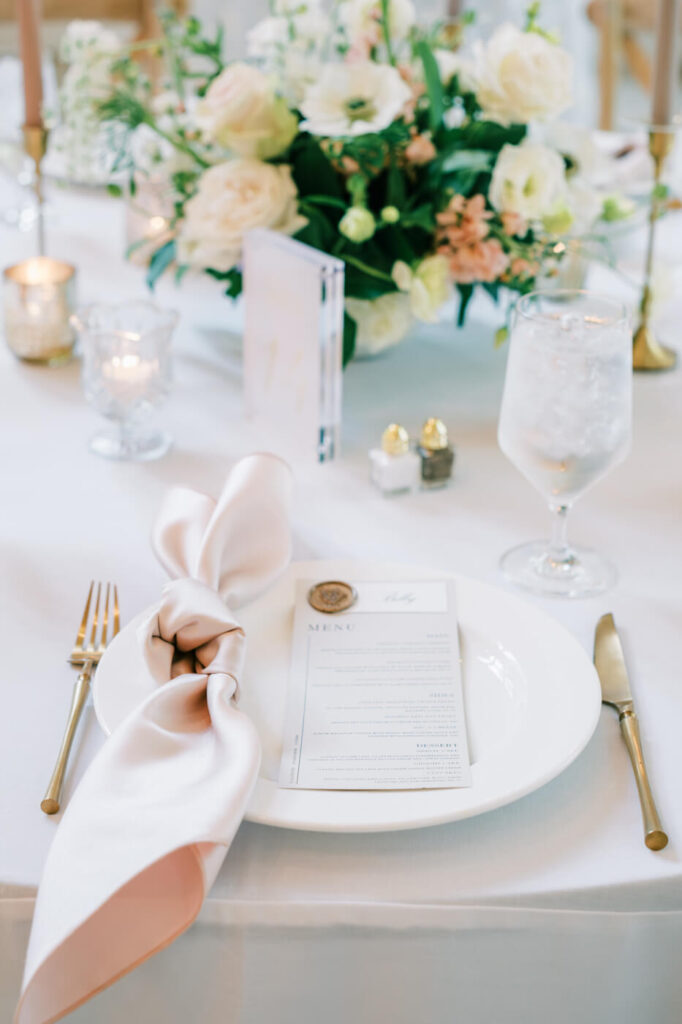 A beautifully set reception table adorned with pastel floral centerpieces, glowing candlelight, and elegant place settings at Carolina Grove.