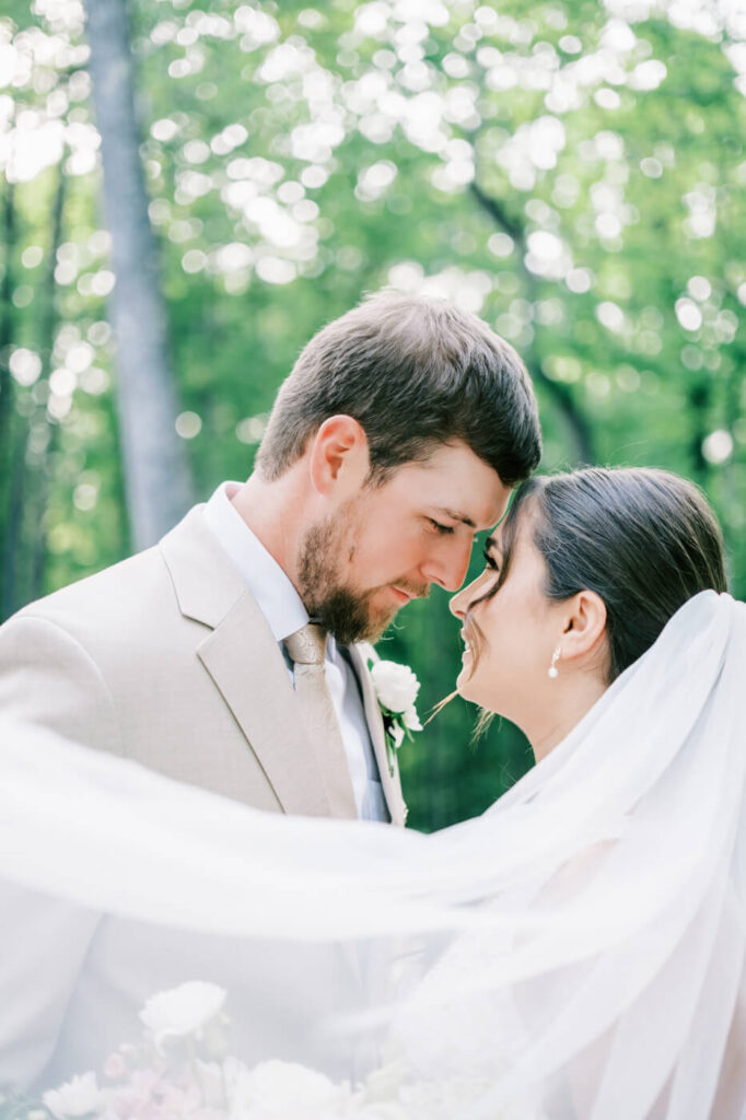 A romantic veil shot of the bride and groom, their foreheads touching intimately as the soft fabric flows around them.