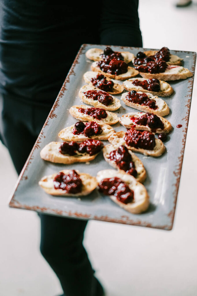 A charming plated appetizer of toasted crostini with berry compote and creamy spread, artfully arranged on a rustic serving platter.