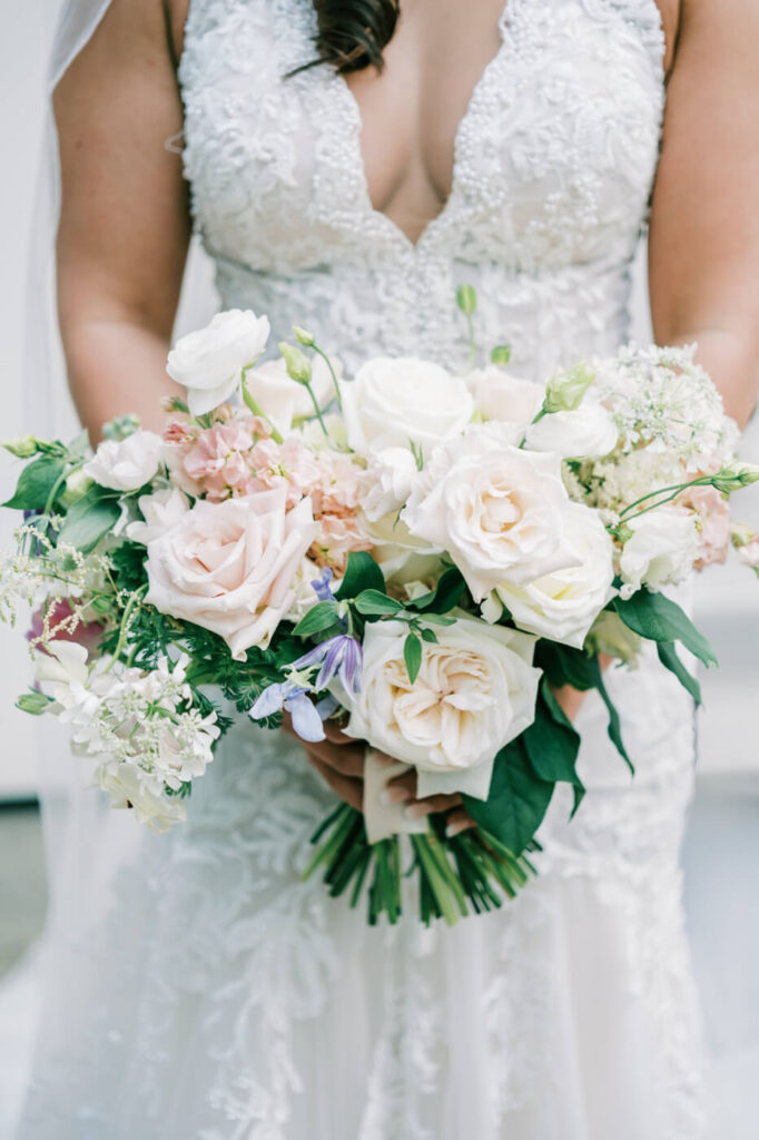 A close-up of the bride’s stunning bouquet featuring lush ivory and blush roses, accented with delicate greenery.