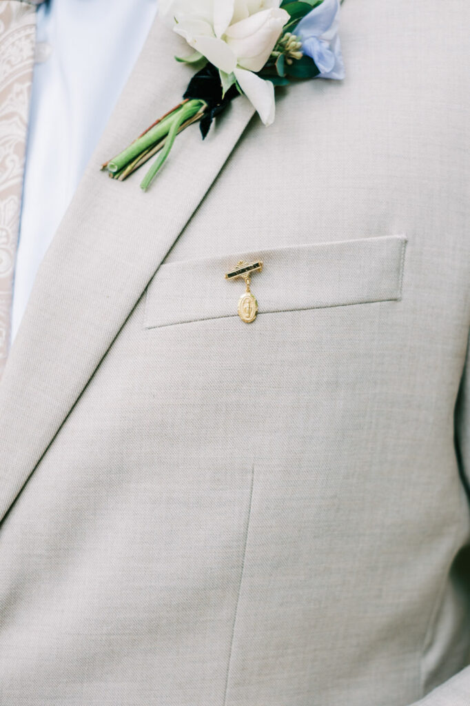 Close-up of groom Aiden's suit details, featuring a white floral boutonnière and a sentimental gold pin.